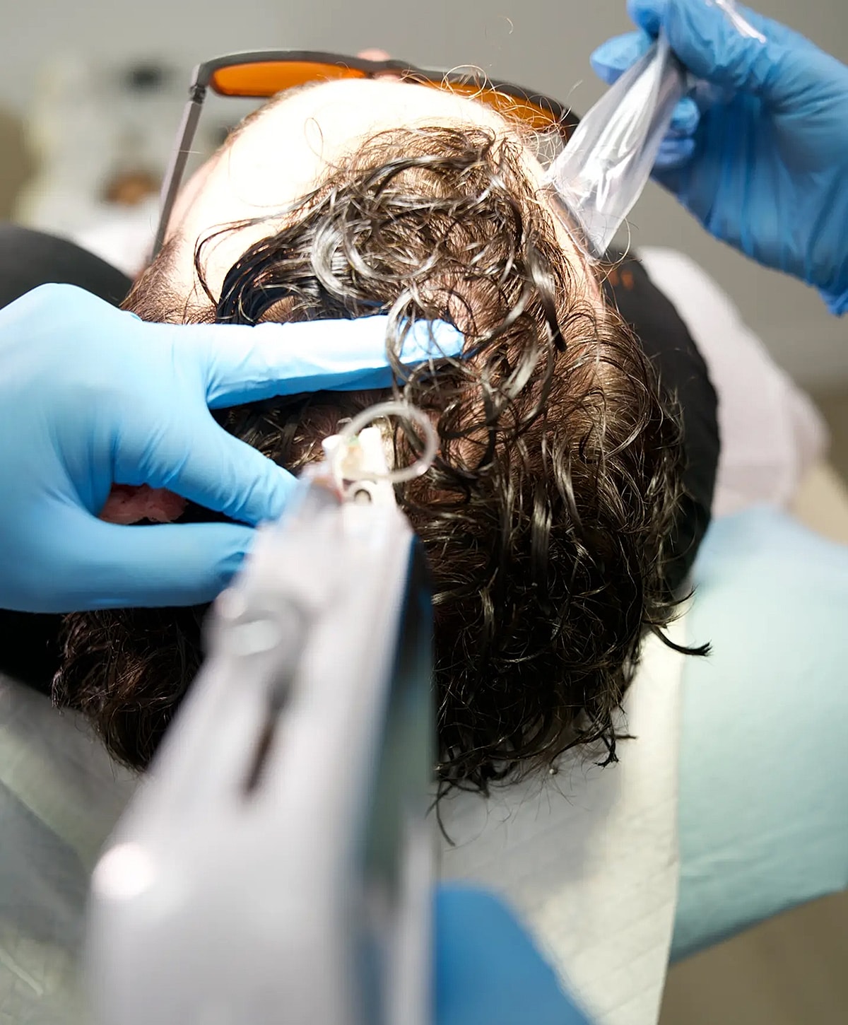 Hair treatment procedure with gloved hands.