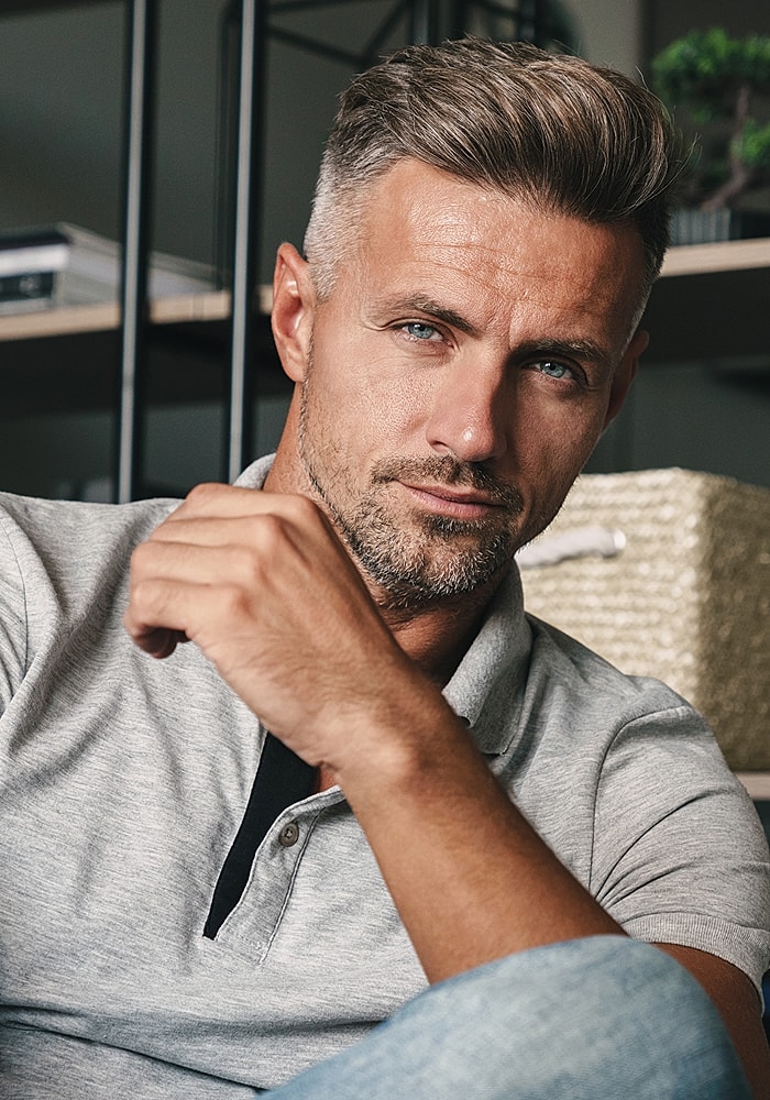 Man with stylish haircut and thoughtful expression.