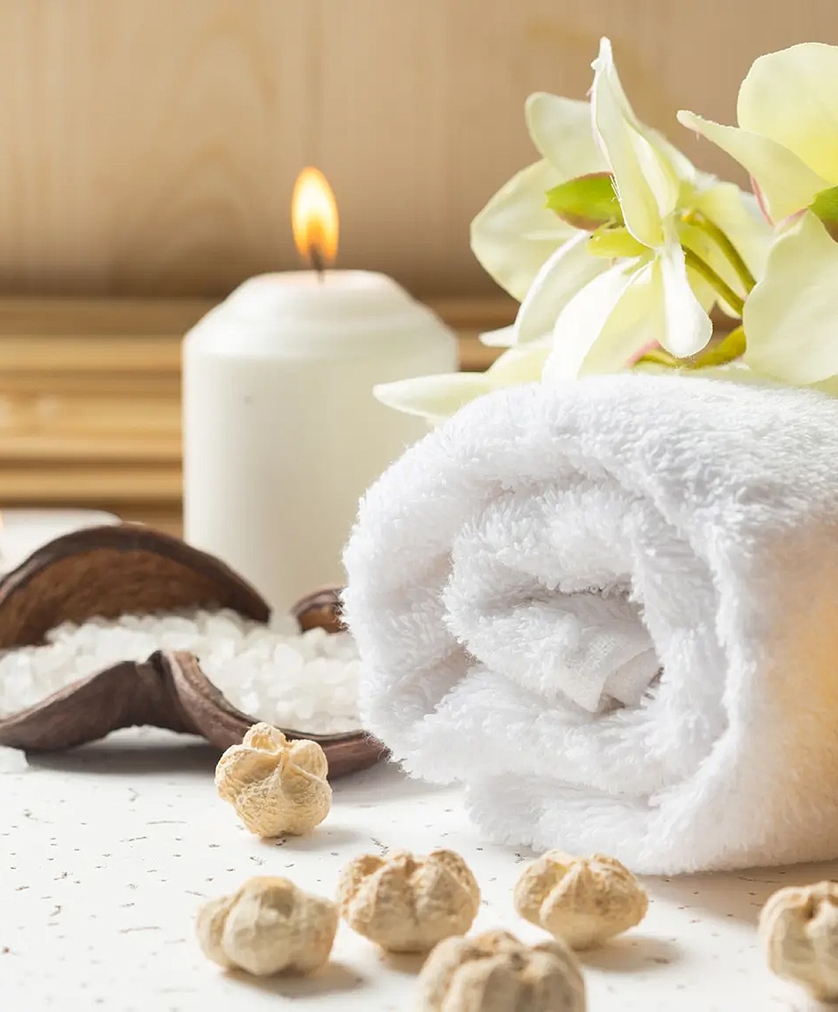 Spa setting with towel, candle, and flowers.
