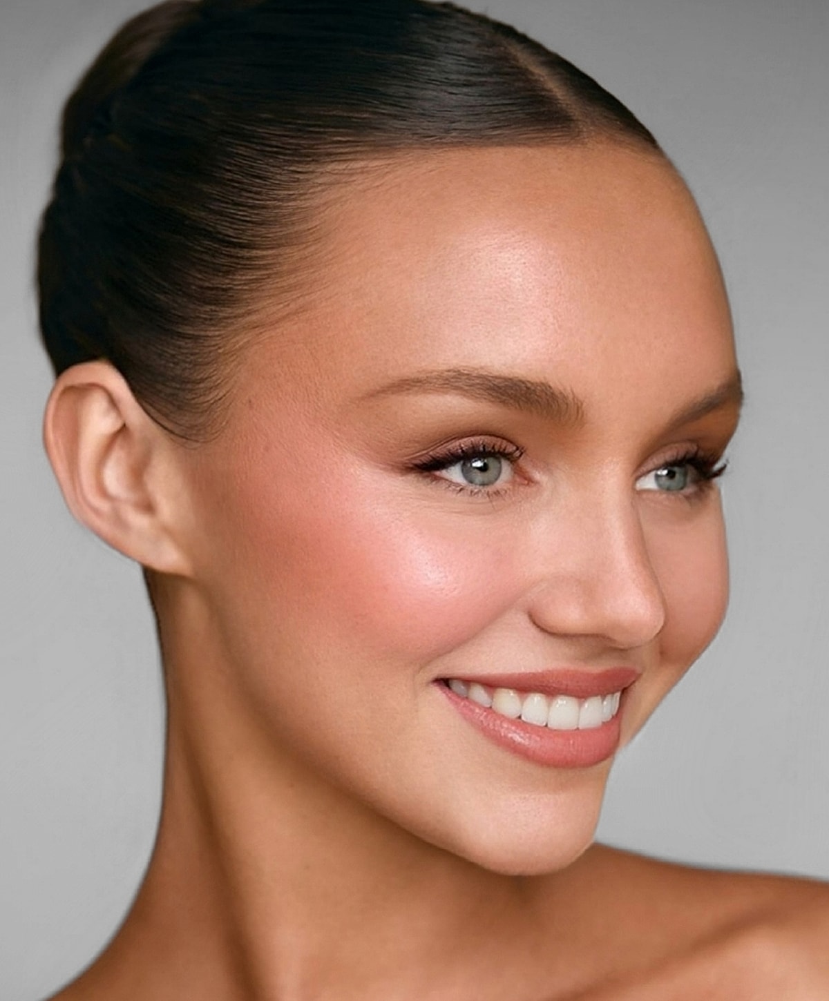 Smiling woman with sleek hairstyle and radiant makeup