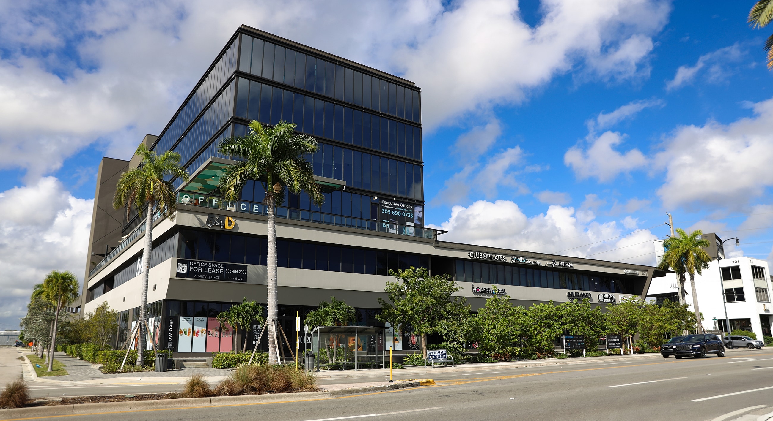Modern office building with palm trees and signage.