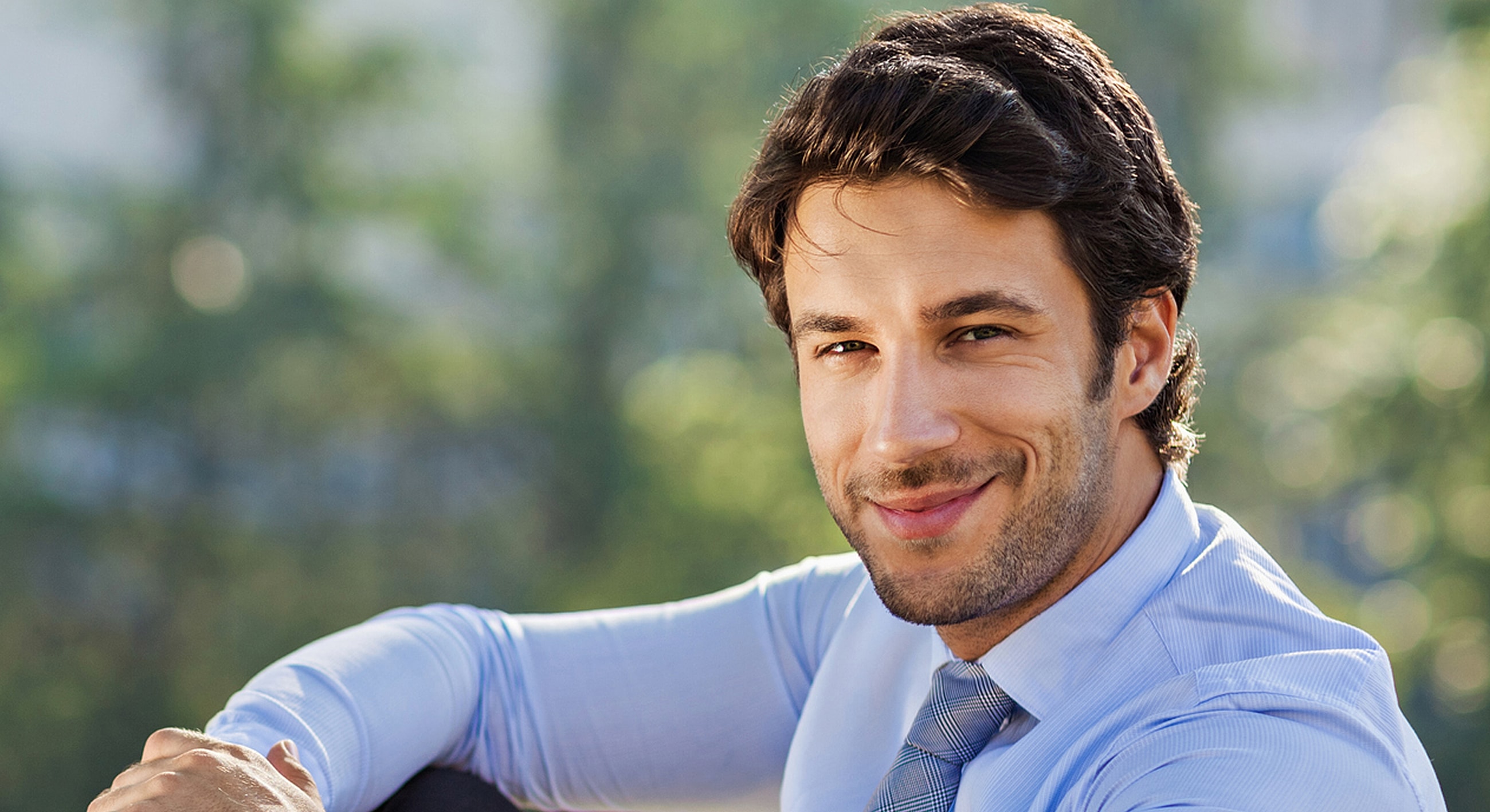 Smiling man in a professional outfit outdoors.